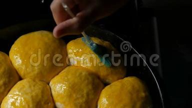 自制烘焙片上，一个女面包师用蛋黄将面团中的小球涂上油脂。 特别厨房