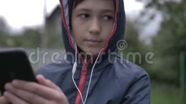 带着耳机的有趣男孩在户外通过电话听音乐