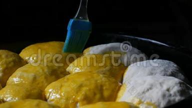 自制烘焙片上，一个女面包师用蛋黄将面团中的小球涂上油脂。 特别厨房
