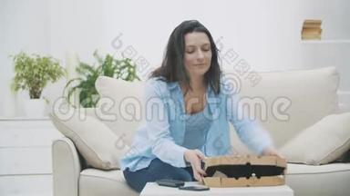 女人打开一个盒子，里面有热腾腾的美味披萨，然后打开电视。 复制空间。 4K.