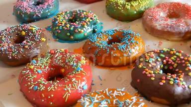 新鲜可口的圆形甜甜圈，有多种颜色的巧克力糖衣，粉色、蓝色、白色、橙色、绿色和各种装饰