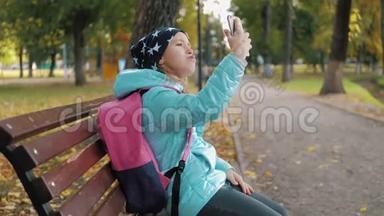 金秋<strong>时节</strong>，一位美丽的少女坐在公园的长椅上，用手机自拍