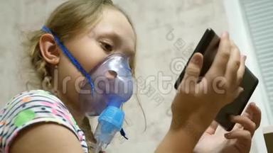 一个戴着面具的生病女孩吸入一个喷雾瓶，在平板<strong>电脑</strong>上<strong>玩电脑</strong>游戏。 戴着蓝色医院面具的<strong>孩子</strong>