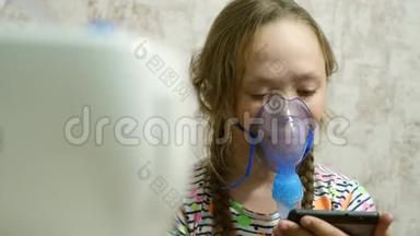 一个戴着面具的生病女孩吸入一个喷雾瓶，在平板电脑上玩电脑游戏。 戴着蓝色医院面具的孩子