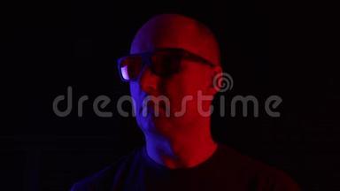 一个戴墨镜的秃头男人，黑底蓝红相间。黑工作室中戴墨镜的成人肖像