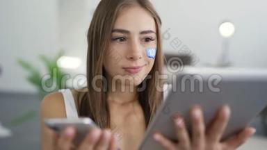 年轻迷人的女人手里拿着手机和平板电脑，微笑着看着相机的肖像。 蓝色留言框