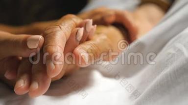 女人温柔地抚摸着母亲照顾她的手。 女儿安慰老妈妈皱着<strong>胳膊</strong>躺在床上