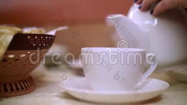 靠近女人的手，拿着茶壶，把热茶倒进前景上的白碗里。 <strong>饮茶</strong>仪式。