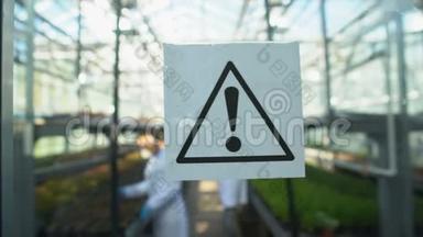 警告标志门打开，农业工程师在温室里使用化学品