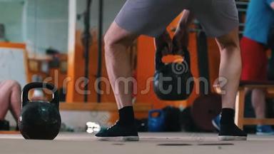 体育训练-在健身房里做运动的男人-一个蹲在前台的男人，手里拿着体重