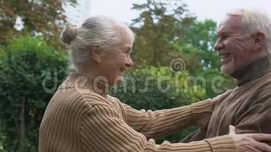 浪漫的一对退休老人在户外约会时拥抱，亲密的关系