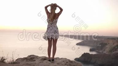从年轻的金发女孩的背面拍摄，站<strong>在悬崖上</strong>欣赏<strong>悬崖上</strong>的景色。 免费