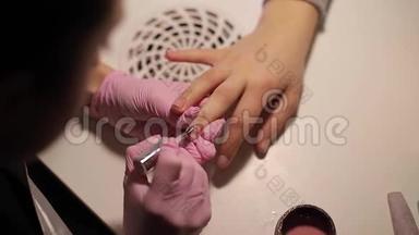 特写女人画指甲。 美甲艺术。 女员工戴粉色手套。 紧紧抓住女人`双手