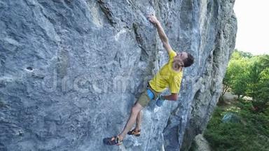 观看身穿黄色t恤、在悬崖上攀岩、在艰苦的运动路线上休息和粉笔的男子攀岩者的角度图