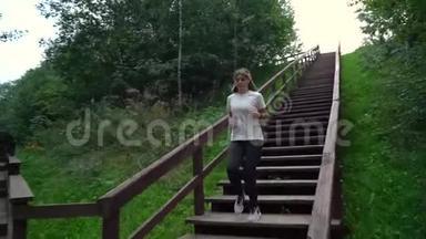 穿着白色t恤和黑色<strong>运动裤</strong>的年轻女孩跑下楼梯，完成她的运动挑战，非常高兴