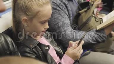 可爱的少女坐在地铁里看着她的手机。 儿童<strong>利用</strong>互联网搜索信息