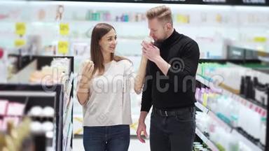 夫妻俩在<strong>化妆品店</strong>里选择奶油，女人打开闻一闻。