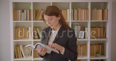 一位年轻的白种人女商人在图书馆里看一本书看照相机的特写肖像