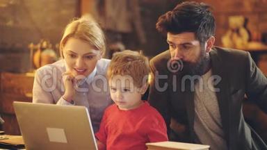 漂亮的年轻父母和他们的孩子在家里使<strong>用笔</strong>记本电脑。 有儿子的年轻家庭一起使<strong>用笔</strong>记本电脑