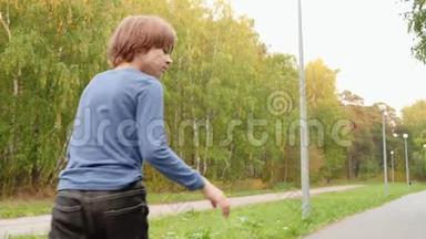 男孩滑板滑板在滑板上的路径在夏季城市公园。 后景少年骑长木板