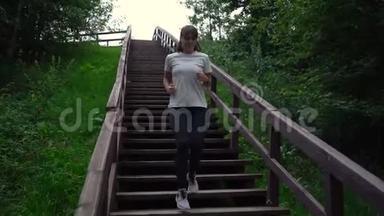 年轻漂亮的女孩或穿着白色T恤和黑色运动裤的女人在公园日落时走下楼梯。