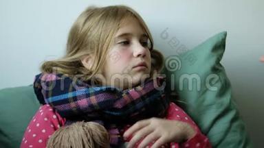 生病的<strong>感冒</strong>小<strong>女孩</strong>正坐在毯子下面，带着围巾喝热凉茶。 有爱心的母亲