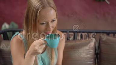 年轻女子坐在漂亮的咖啡馆里享受蓝色<strong>拿</strong>铁。 热蝶豌豆<strong>拿</strong>铁或蓝色螺旋藻<strong>拿</strong>铁.. 慢动作