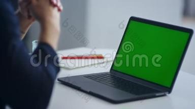 看不见的人看着绿色屏幕笔记本电脑。 商人工作笔记本