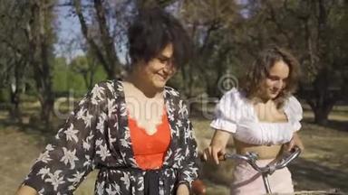 两个穿着鲜艳衣服的可爱女人在街上狭窄的路上牵着自行车说话。 农村生活