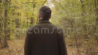 一个白人成年人站在森林里<strong>四处</strong>张望。 穿着休闲服装的男人，享受着宁静