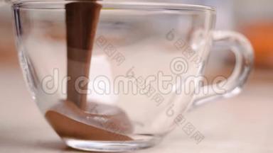 把光滑美味的融化的黑巧克力或牛奶巧克力倒入白色的杯子碗里。 特写镜头。 有机巧克力糖霜