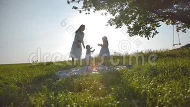 幸福的家庭的妈妈和两个小女儿正在一片远离城市的草地上休息。