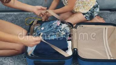 妈妈正在包装一个巨大的蓝色手提箱。 小女孩在抓她。 为旅行做准备。 快关门。 4K.
