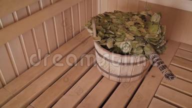 木制桑拿浴室中的各种桑拿配件。 带有扫帚的桑拿浴室的内部