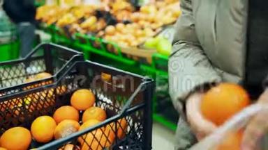 超市里的一个女人从一个盒子里拿出橘子放进一个袋子里。 把橘子放进抽屉里。
