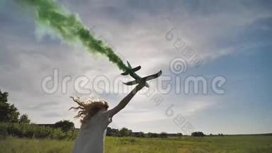 漂亮的女孩带着一架发出彩色烟雾的玩具飞机跑步。 工作飞机的错觉..