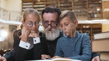 带着迷人的微笑的孙子孙女们和他们尊敬的老爷爷一起坐在图书馆看书