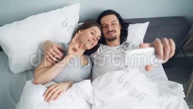 大胡子男和女友用智能手机摄像头在床上自拍