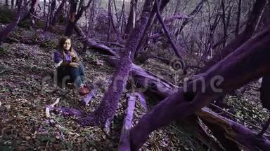 紫罗兰童话森林.. 穿着淡紫色夹克的漂亮女孩坐在一片美丽的淡紫色森林里，看着她的花朵