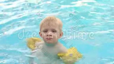 带着<strong>充气</strong>套的小男孩在室外的游<strong>泳池</strong>里游泳。