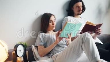 穿着睡衣的男人和女人在床上看书，在家翻页