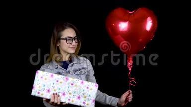一个年轻的女孩站着拿着礼物和心形气球。 一个女人手里拿着礼物和氦气球
