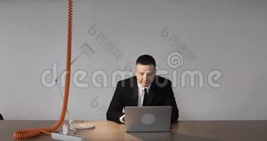 成熟的男士办公室工作人员西装革履的笔记本<strong>电脑坐在</strong>桌子<strong>前</strong>看。