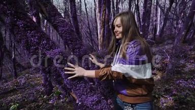 紫罗兰童话森林.. 美丽快乐的女孩在阳光明媚的日子里，抚摸着一棵树干，树干上长满了厚厚的紫色苔藓