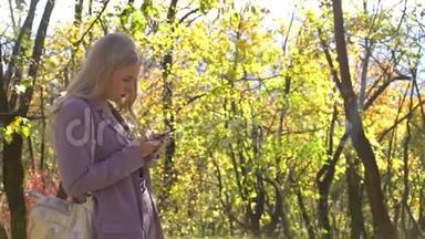 金发商务女孩与智能手机停留秋季森林公园花园技术自然美丽幻想自然