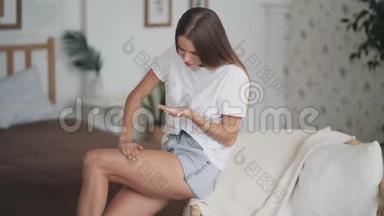 年轻女子坐在扶手椅上，在腿上涂防滑霜