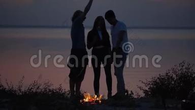 三个年轻的<strong>潮</strong>人朋友在海边篝火烤棉花糖，在炎炎<strong>夏日</strong>聊天