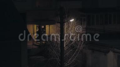 一个柱子上的灯笼在房子附近的夜晚发光，有人离开入口