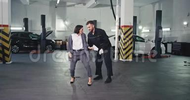 时尚的经理女人穿着西装，一个男<strong>机修工</strong>在一台现代的照相机前兴奋地跳舞