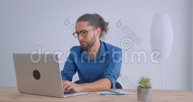 现代商人，<strong>扎</strong>着马尾辫，戴着眼镜，用笔记本电脑工作，在白色办公室专<strong>心</strong>做笔记。